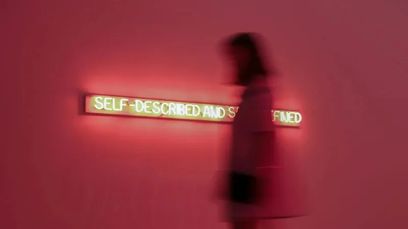 Blurred image of person walking by a sign that says Self-Described, Self-Defined