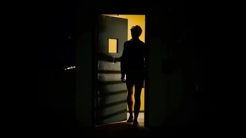A shadowy figure hesitating at a doorway, representing the fear of starting a business.